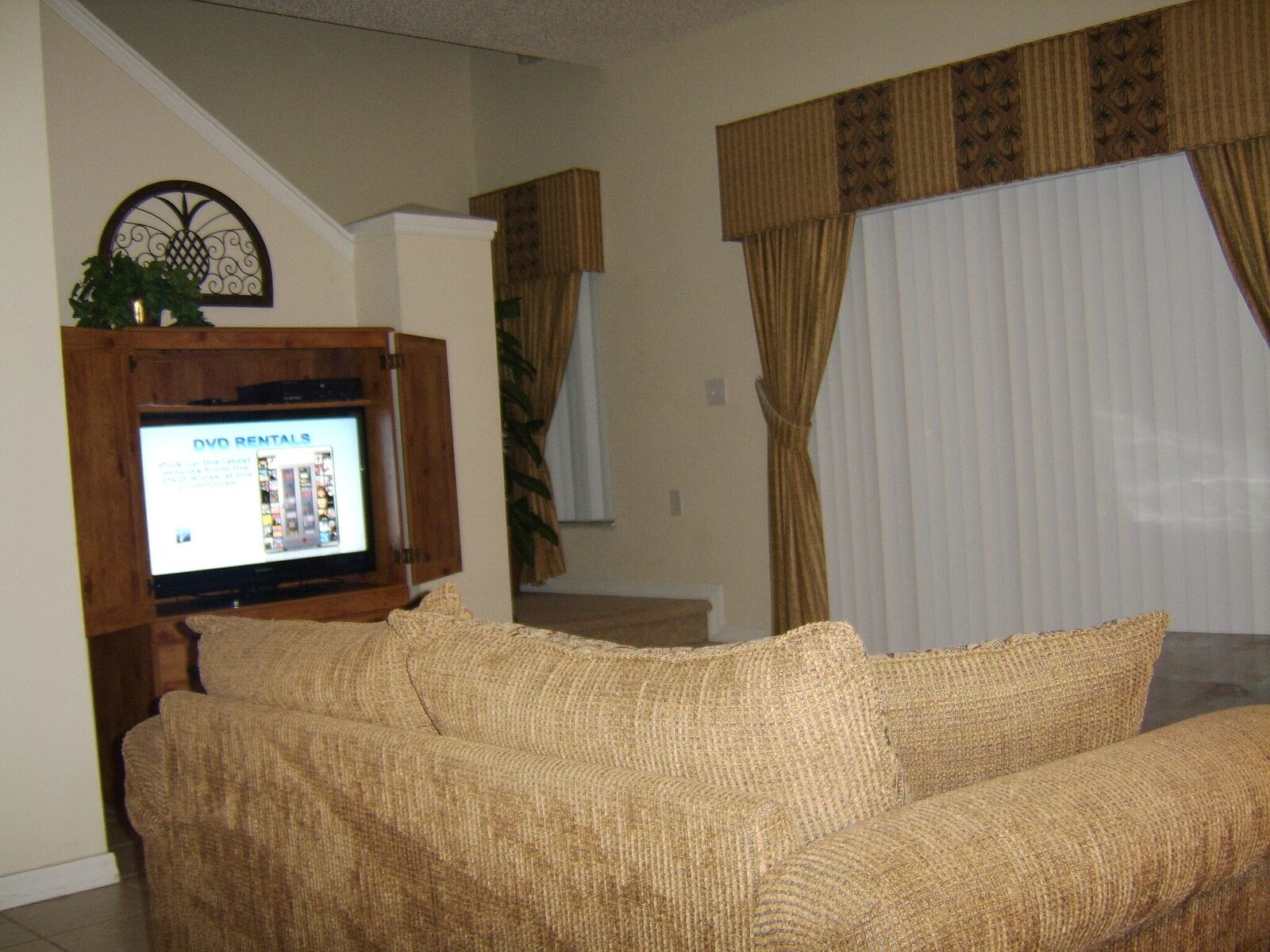 Sofa facing a television in a wooden cabinet, with palm-pattern curtains