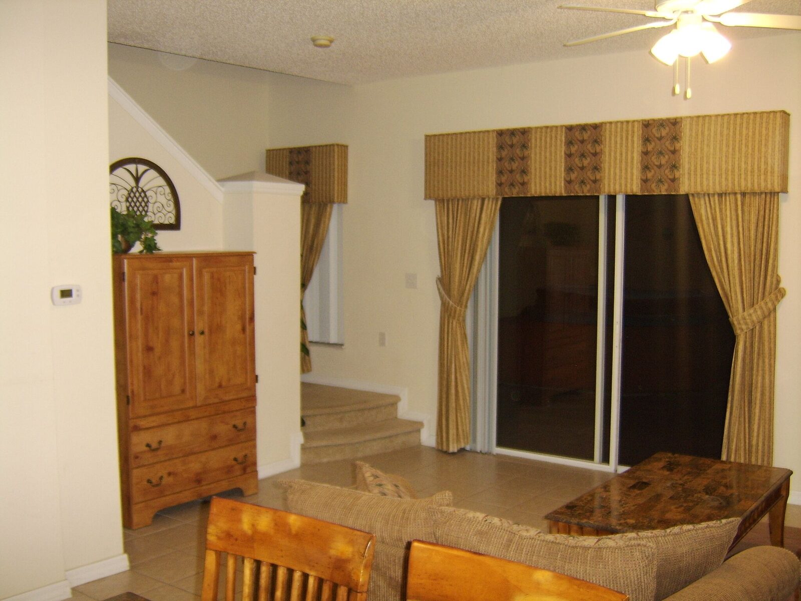Sliding glass doors from the living room onto the screened patio, with a ceiling fan and wooden cabinet
