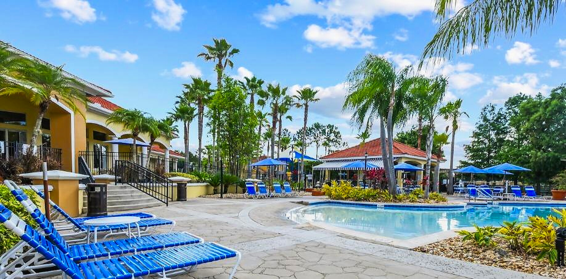 The Terra Verde clubhouse pool in daylight, with lounge chairs, palms, and the tiki bar