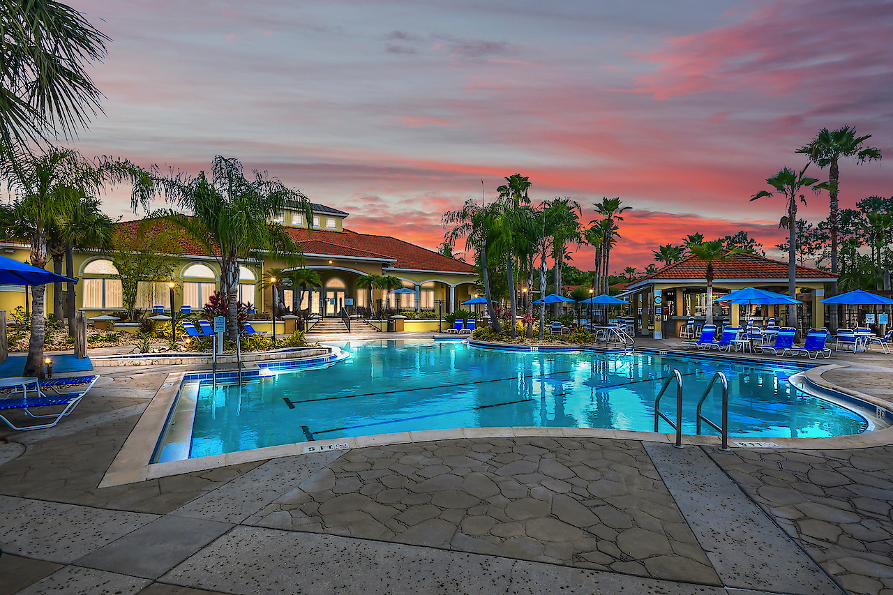 Terra Verde's heated clubhouse pool at sunset, with the tiki bar, palms, and lounge chairs
