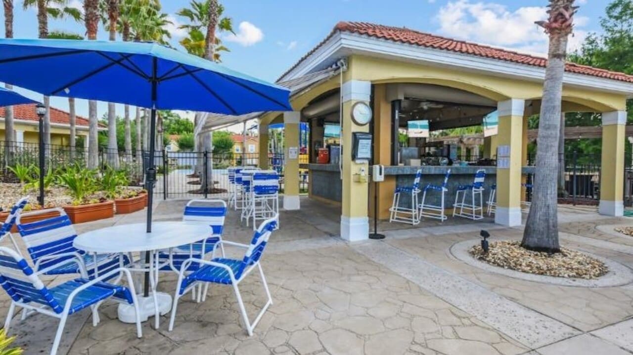 Terra Verde poolside bar with a blue umbrella, striped chairs, and the open counter