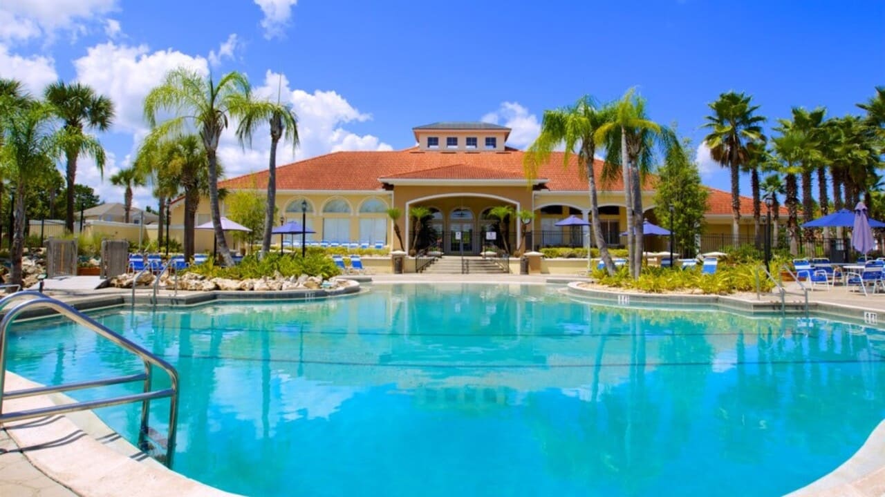 Turquoise clubhouse pool in front of the Terra Verde clubhouse, palms, and a blue sky